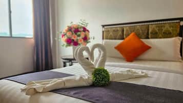 Een netjes opgemaakt bed met een decoratieve handdoeksculptuur en een bloemstuk.