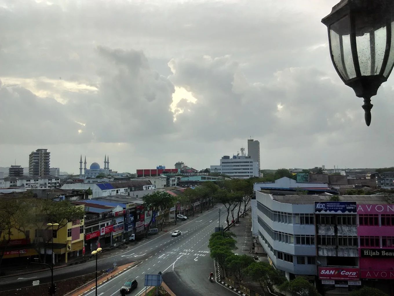 A cityscape with a road, buildings, and a mosque with two minarets.
