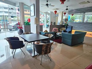 A modern hotel lobby with a reception desk, seating area, and large windows offering a view of the street. - Swing & Pillows - Bandar Kuantan (Kuantan)
