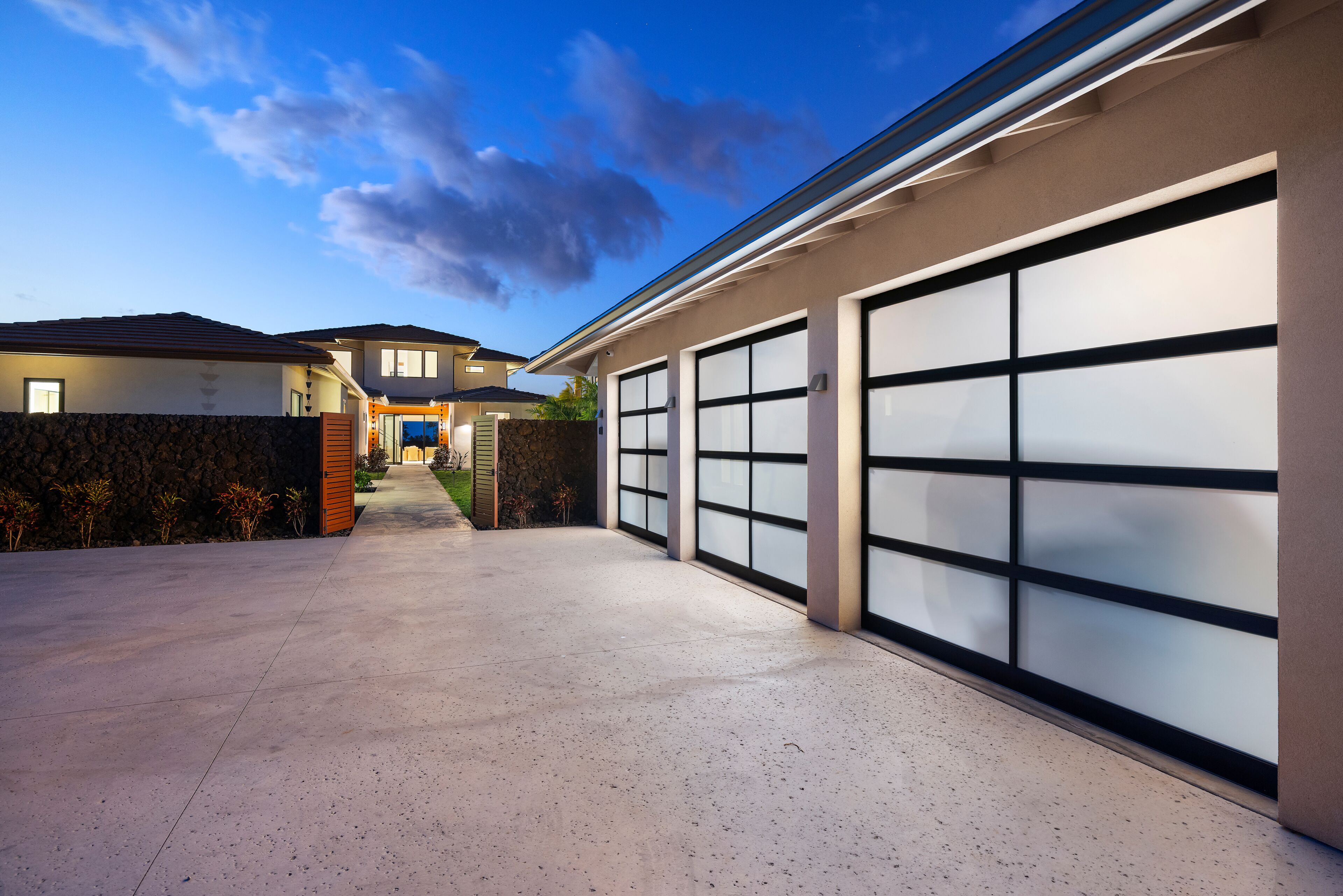A modern two-story house with a garage, a driveway, and a stone wall.