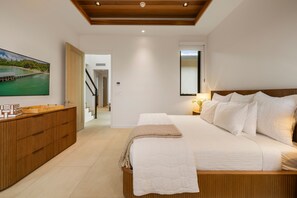 A bedroom with a large bed, a wooden dresser, a television, and a view of a pier through a window. - Exquisite 6BR One Ocean Estate (GE5) at Mauna Lani – Ocean Views & Infinity Pool (Kamuela)