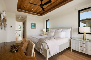 Ein Schlafzimmer mit Bett, Nachttischen, Deckenventilator, Fenster und Blick ins Freie.