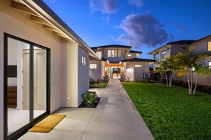 A modern residential property with a covered patio, a well-maintained lawn, and a clear sky. - Exquisite 6BR One Ocean Estate (GE5) at Mauna Lani – Ocean Views & Infinity Pool (Kamuela)