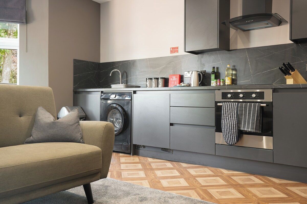 Une cuisine moderne équipée d’un lave-linge, d’un four, et d’un canapé dans l’espace de vie attenant.