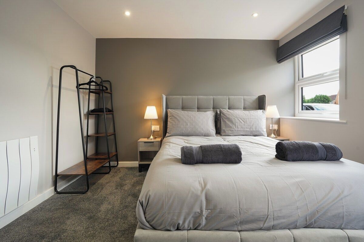 A bedroom with a bed, bedside lamps, a window, and a radiator.