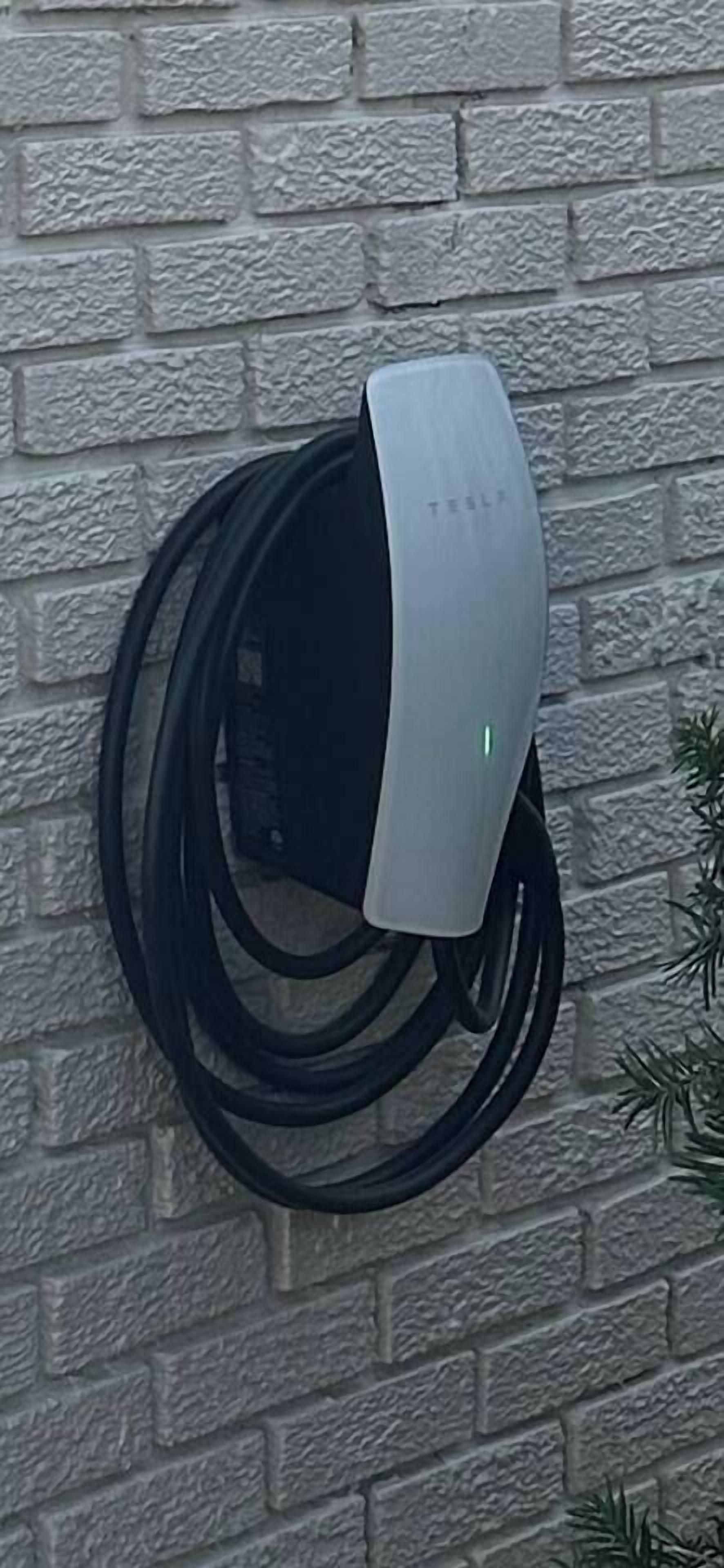 Eine Tesla Ladestation, an einer Ziegelwand angebracht.