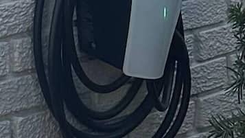 Eine Tesla Ladestation, an einer Ziegelwand angebracht.