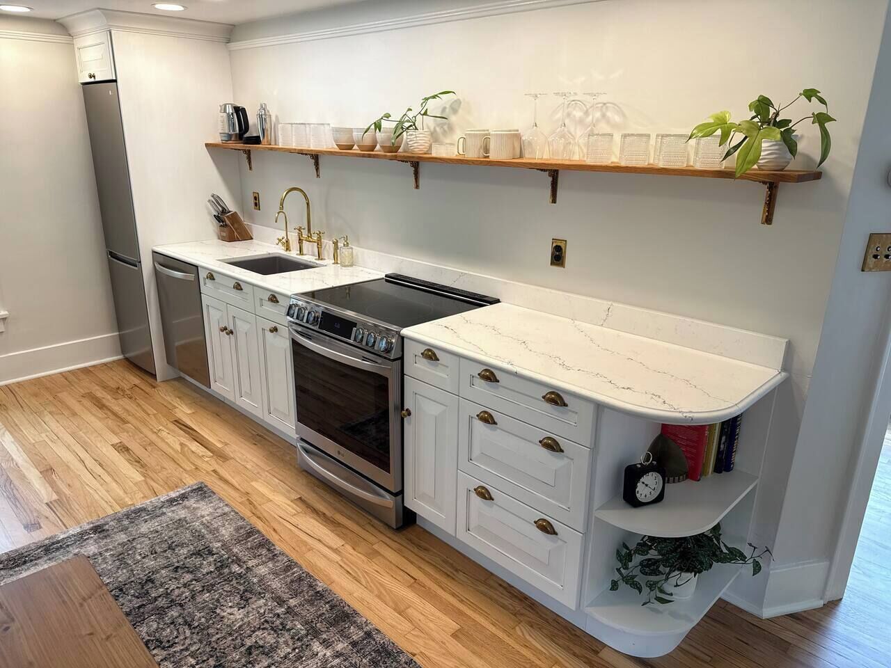 A kitchen with white cabinetry, a built-in oven, and a stainless steel refrigerator.