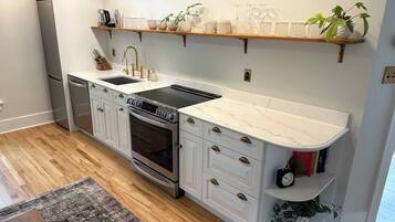 A kitchen with white cabinetry, a built-in oven, and a stainless steel refrigerator.
