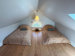 A room with two beds, a skylight, and a hanging light fixture.