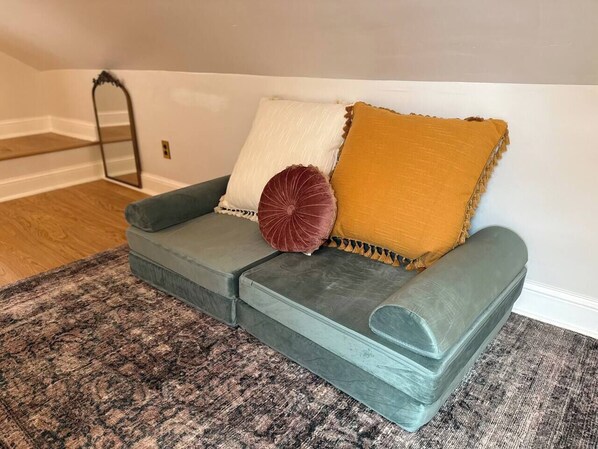 A grey sectional sofa with a white and mustard throw pillow, a red accent pillow, and a grey accent pillow.