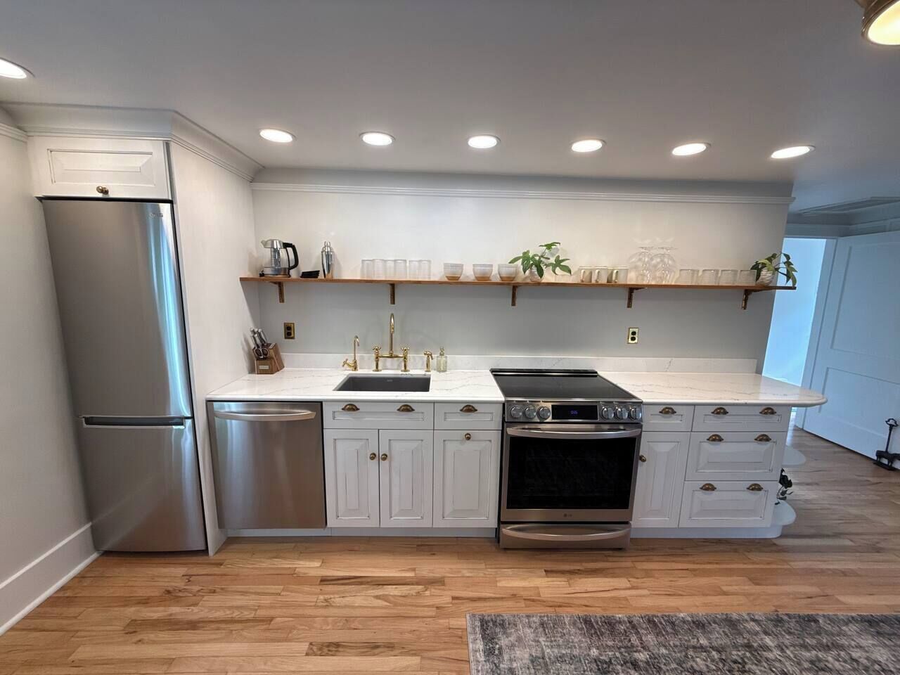 Una cocina moderna con refrigerador de acero inoxidable, horno empotrado y encimera con pileta.