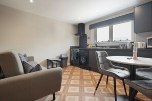 A compact living space with a kitchenette, a dining area, and a sofa. - The Olive Tree | Cozy Deluxe 2-Bed (Kingston upon Hull)