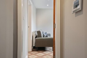 A narrow hallway leading to a room with a bed and a radiator. - The Olive Tree | Cozy Deluxe 2-Bed (Kingston upon Hull)