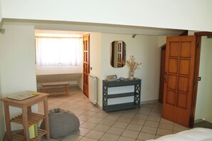 A bedroom with a bed, a bedside table, a radiator, a mirror, and a door.