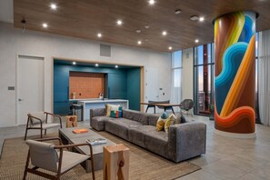 A modern lounge area with a sectional sofa, armchairs, a coffee table, and a colorful column. - 24th-floor 1BR Sleeps 4 | Rainey + Rooftop Pool (Austin)