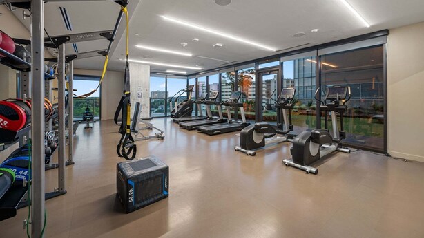 A gym with treadmills, weight machines, and a TRX suspension trainer. - 24th-floor 1BR Sleeps 4 | Rainey + Rooftop Pool (Austin)