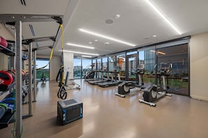 Ein Fitnessstudio mit Laufbändern, Kraftgeräten und einem TRX-Suspension-Trainer.