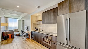 A modern kitchen with a large stainless steel refrigerator, a built-in oven, and a dining area with a table and chairs. - 24th-floor 1BR Sleeps 4 | Rainey + Rooftop Pool (Austin)