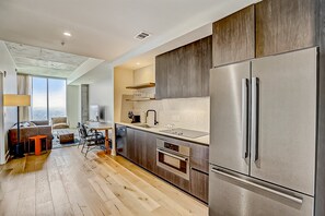 A modern kitchen with a large stainless steel refrigerator, a built-in oven, and a dining area with a table and chairs. - 24th-floor 1BR Sleeps 4 | Rainey + Rooftop Pool (Austin)