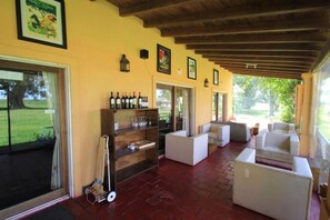 Un espace extérieur abrité, doté d’un sol en briques, de mobilier blanc et d’un présentoir à bouteilles.