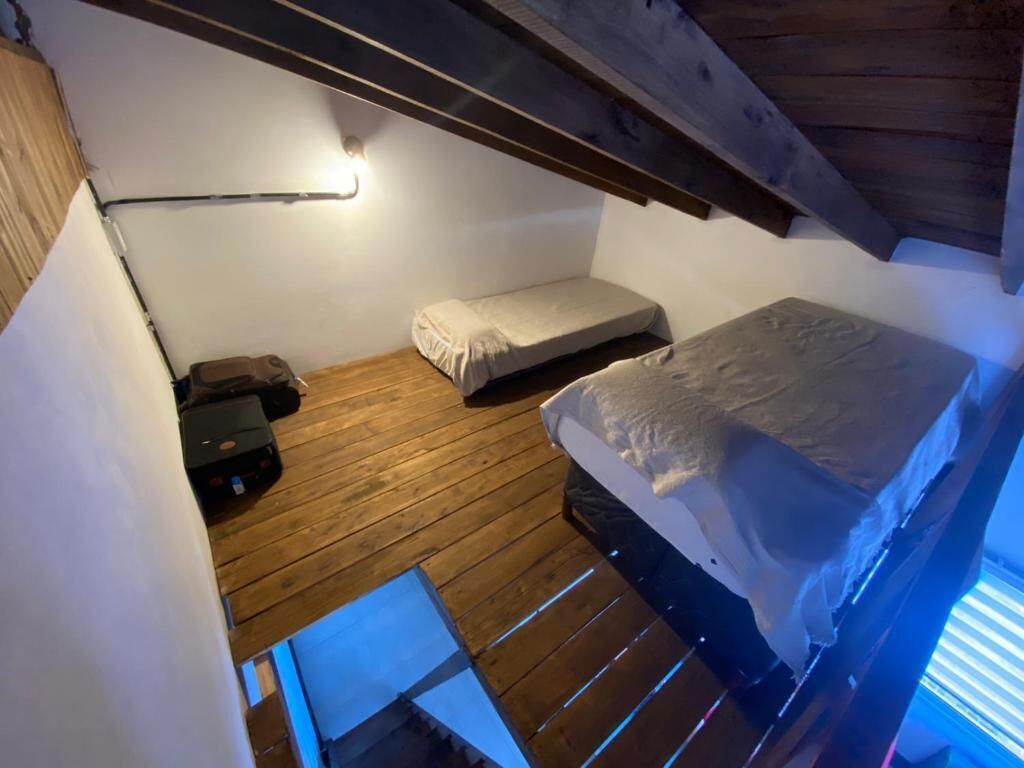 Una habitación compacta con una litera, una mesita de noche pequeña y una lámpara fijada a la pared.