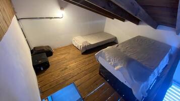 Una habitación compacta con una litera, una mesita de noche pequeña y una lámpara fijada a la pared.