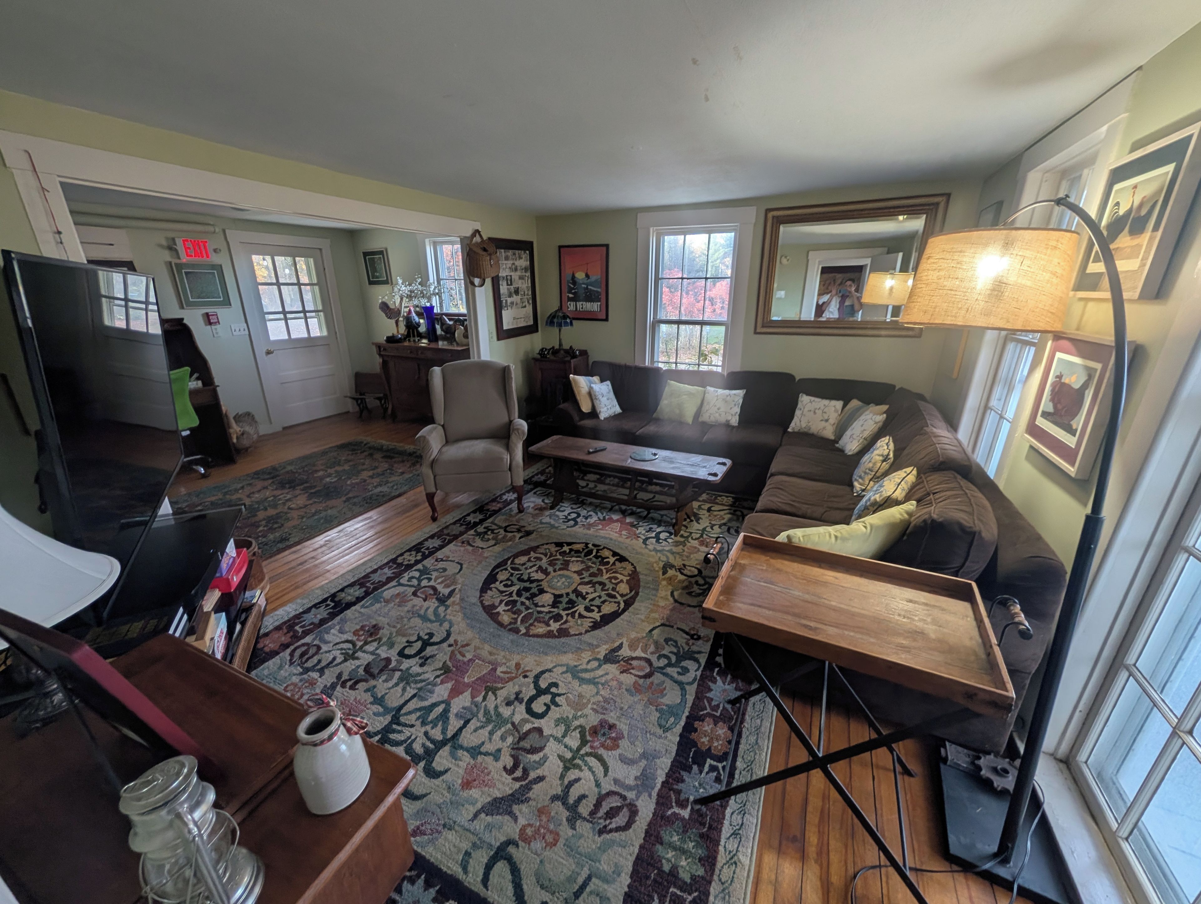 A living room with a sofa, armchair, coffee table, rug, and a lamp.