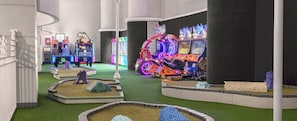An indoor amusement area with various arcade games and a neon-lit motorcycle. - Two-Bedroom Condo on Daytona Beach (Daytona Beach)