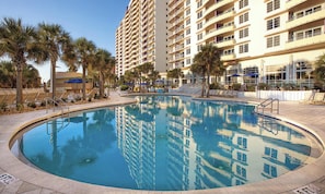 A swimming pool surrounded by palm trees and a multi-story building. - Two-Bedroom Condo on Daytona Beach (Daytona Beach)