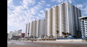 A beachfront hotel with multiple high-rise buildings, a sandy beach, and a clear sky. - Two-Bedroom Condo on Daytona Beach (Daytona Beach)