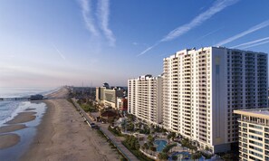 Un hotel sulla spiaggia con diversi edifici alti, una spiaggia sabbiosa e un molo che si estende nell'oceano.