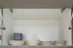Een keukenkastje met een witte binnenkant, met daar een stapel borden en kommen.