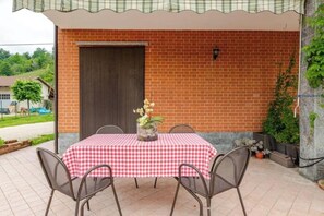 A patio area with a checkered tablecloth, metal chairs, a potted plant, and a brick wall. - Casa Emy da Teresina – Relax in a Green Setting Just a Stone's Throw from Alba (Reala)