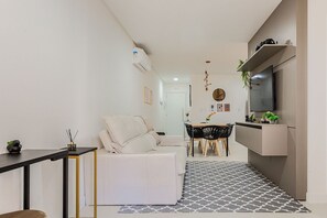 Een moderne keuken met een ingebouwde oven, een eetgedeelte met een tafel en stoelen, en een zithoek met een bank en salontafel.