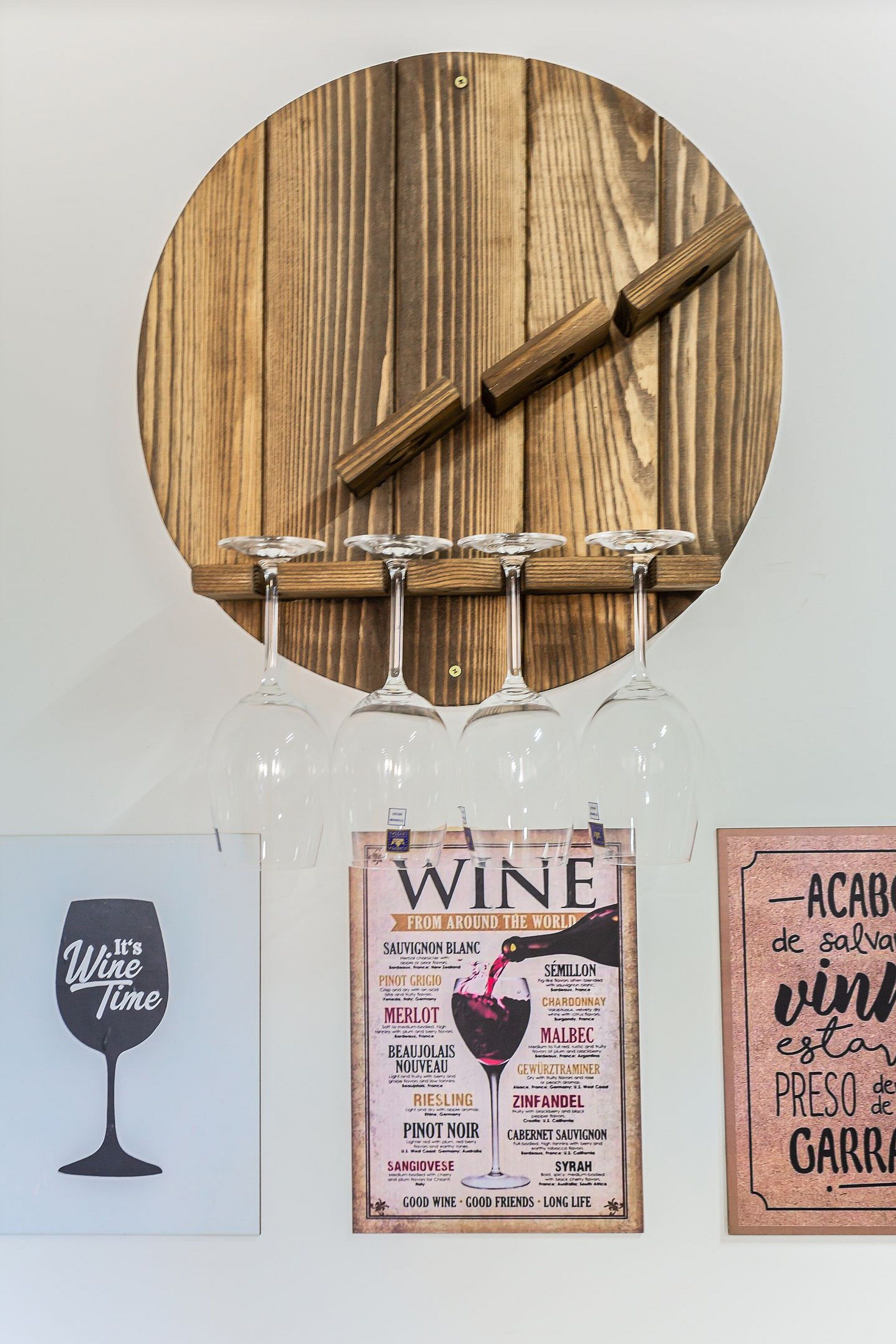 A wine rack with six glasses hanging on a wall, a framed wine list, and a wine glass cutout with the phrase 'It's Wine Time'.