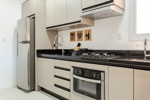 A modern kitchen with a built-in refrigerator, stove, oven, and a stainless steel range hood. - 500m from the sea | pool | Barbecue grill #IA38 (Florianópolis)