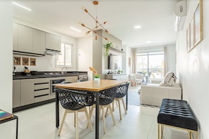A modern kitchen with a dining area, a sofa, and a TV. - 500m from the sea | pool | Barbecue grill #IA38 (Florianópolis)