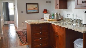 A kitchen with wooden cabinets, granite countertops, a sink, and a red lamp.