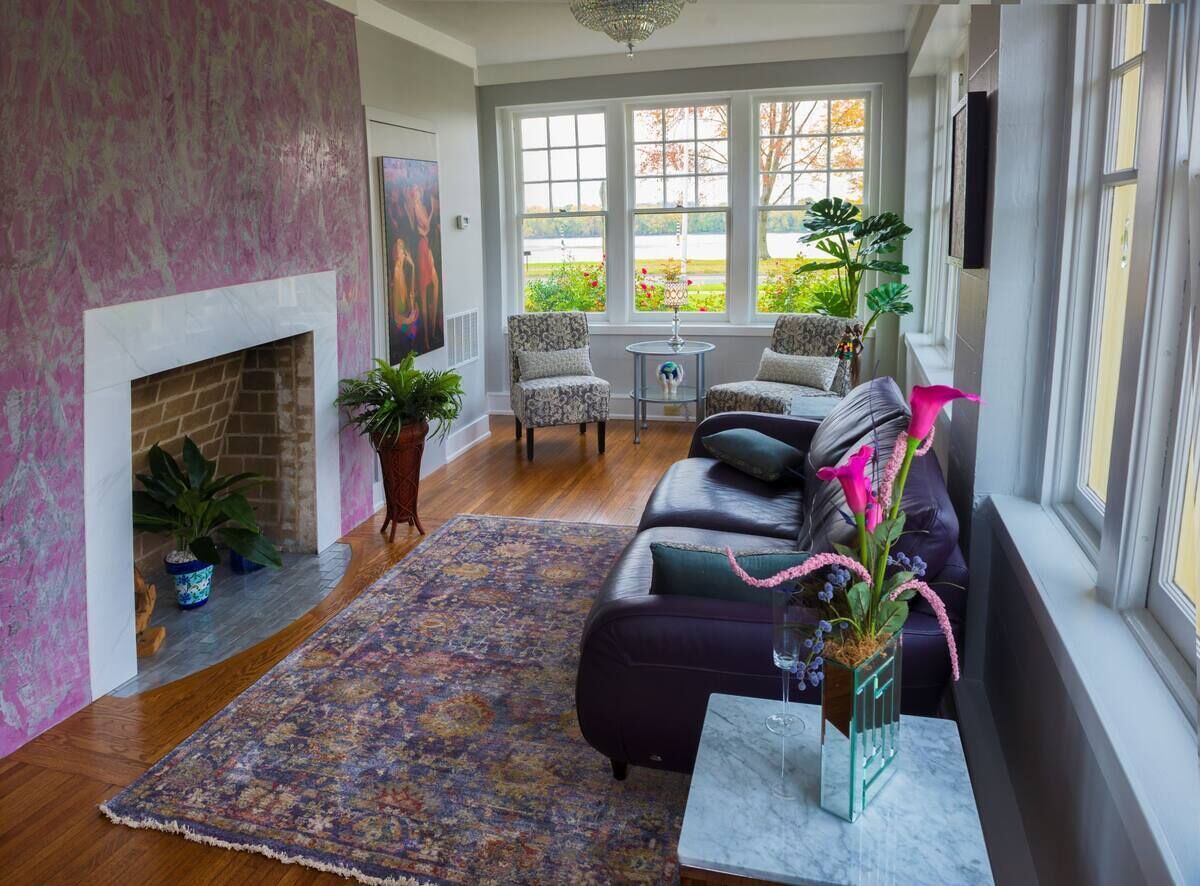 A living room with a fireplace, a sofa, a coffee table, and a view through large windows.