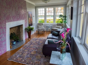 A living room with a fireplace, a sofa, a coffee table, and a view through large windows.