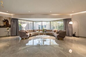 A modern living room with a curved sectional sofa, a glass coffee table, and a floor lamp.