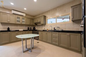 A modern kitchen with beige cabinetry, a central island, and a window providing natural light.