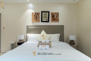 A hotel room with a large bed, two bedside tables, and artwork on the wall.