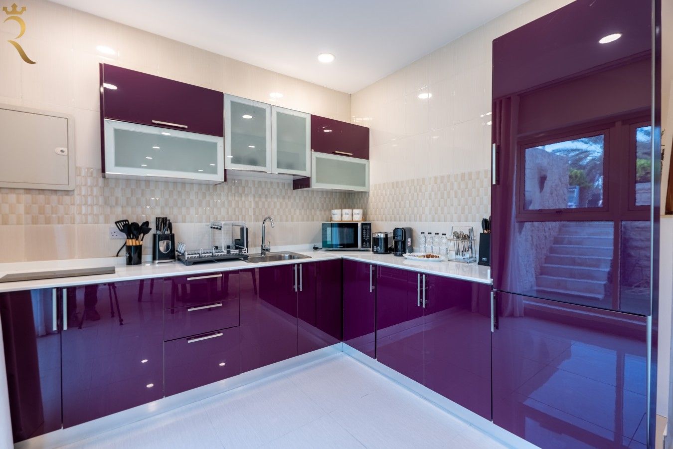 A modern kitchen with purple cabinets, a microwave, and a coffee maker.