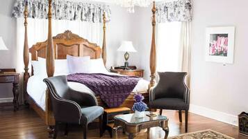 Quarto com cama de dossel, duas poltronas estofadas, mesa de cabeceira e criado-mudo.