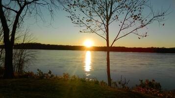 Um lago tranquilo ao pôr do sol, com árvores na margem.
