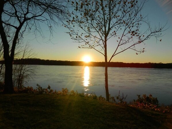 A calm lake at sunset with trees on the shore.