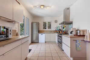 Une cuisine moderne dotée d’appareils électroménagers en acier inoxydable, d’un plan de travail en bois et d’un sol carrelé.
