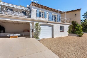 A two-story house with a covered garage, a balcony with white railings, and a small garden area. - Holiday Home 'Les Loriots' with Private Pool, Wi-Fi, and Air Conditioning (Flassans-sur-Issole)